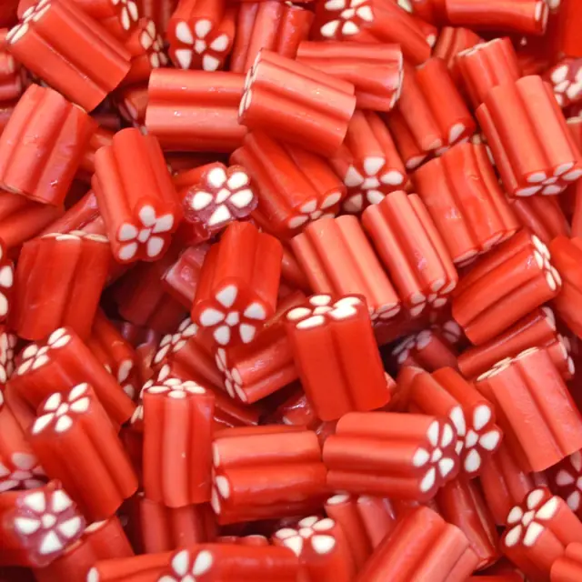 A spread of red strawberry candy pieces with white flower-shaped cream centers