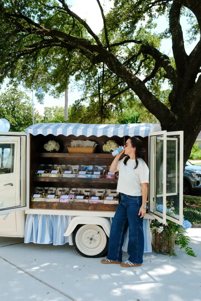 Chelcie Aldred beside the open Haus Candy Cart under an oak tree