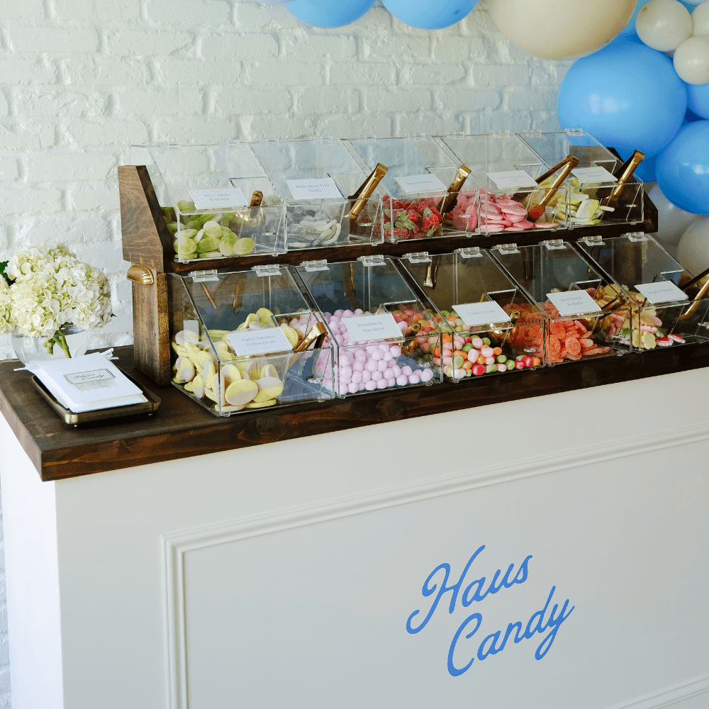 White Haus Candy Stand stocked with candy beneath blue-and-cream balloons