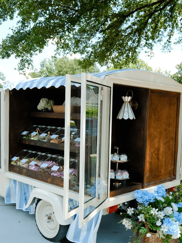 Side view of the Cart with open glass doors, a gold candy-cup stand, and blue hydrangeas