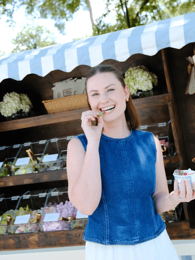 A guest tastes a gummy while holding a Haus Candy cup beside the Cart