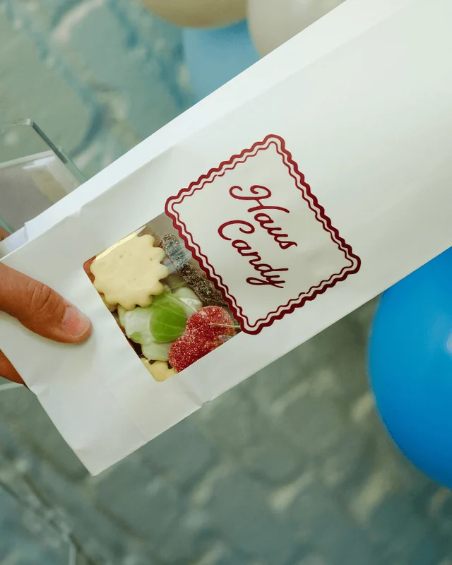 A filled white Haus Candy bag with a clear window showing its colorful candy mix