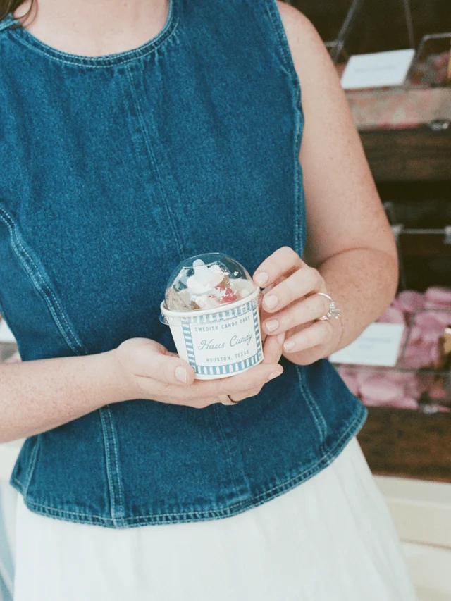 A guest holds a blue-and-white Haus Candy cup filled with sweets under a clear dome lid