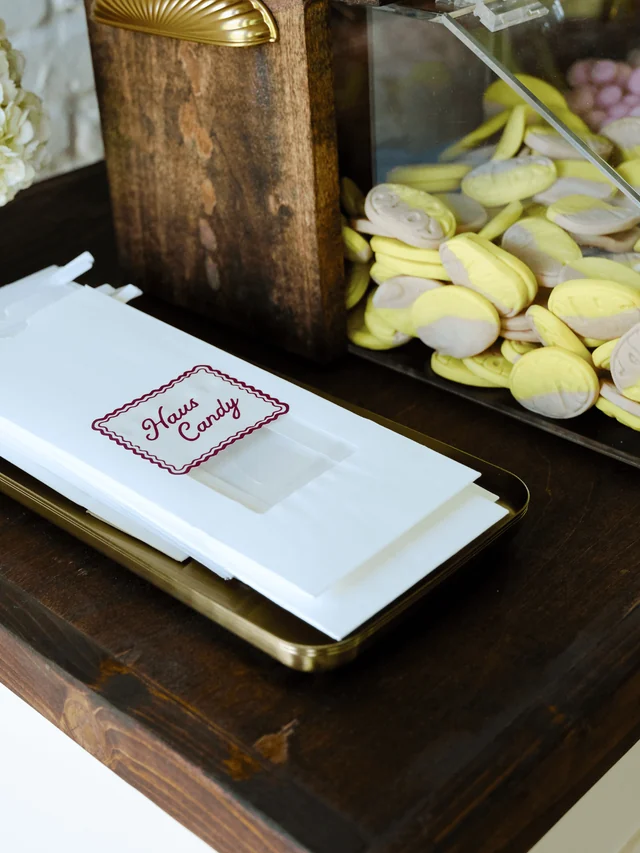 Empty Haus Candy bags rest on a gold tray beside a bin of yellow banana toffee candies